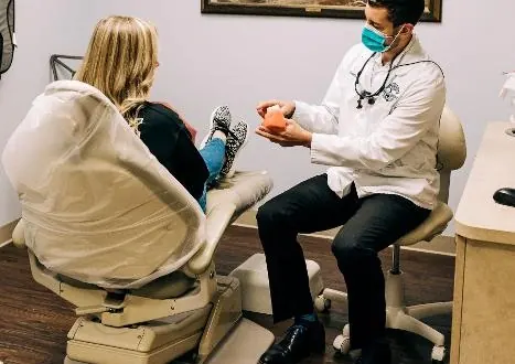 Dr. Blake Nelson, masked, explaining a treatment to a patient in the dental chair.