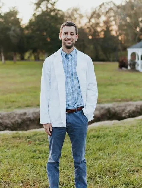 Dr. Blake Nelson standing on a lawn in his white coat.