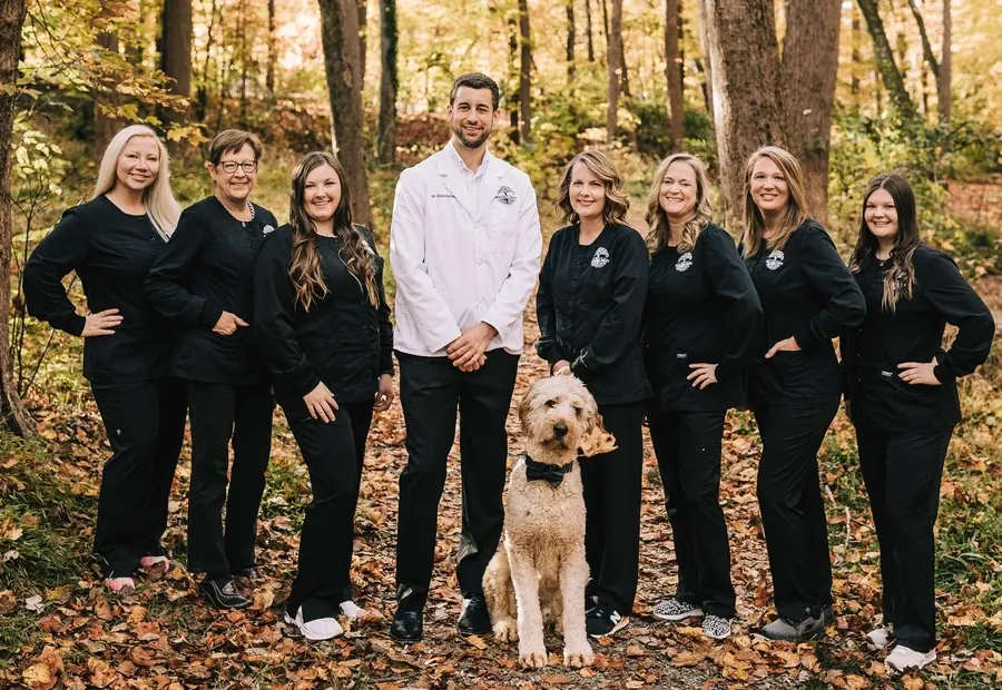 Dr. Blake Nelson and the team, with a goldendoodle, photographed outdoors in autumn.